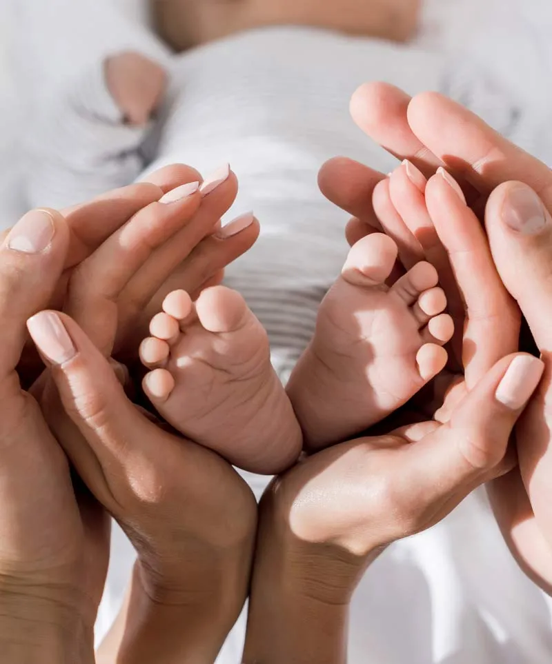 Babyfüße in den Händen der Eltern
